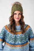 Olive cable-knit pom hat with ribbed cuff and chunky textured knit.