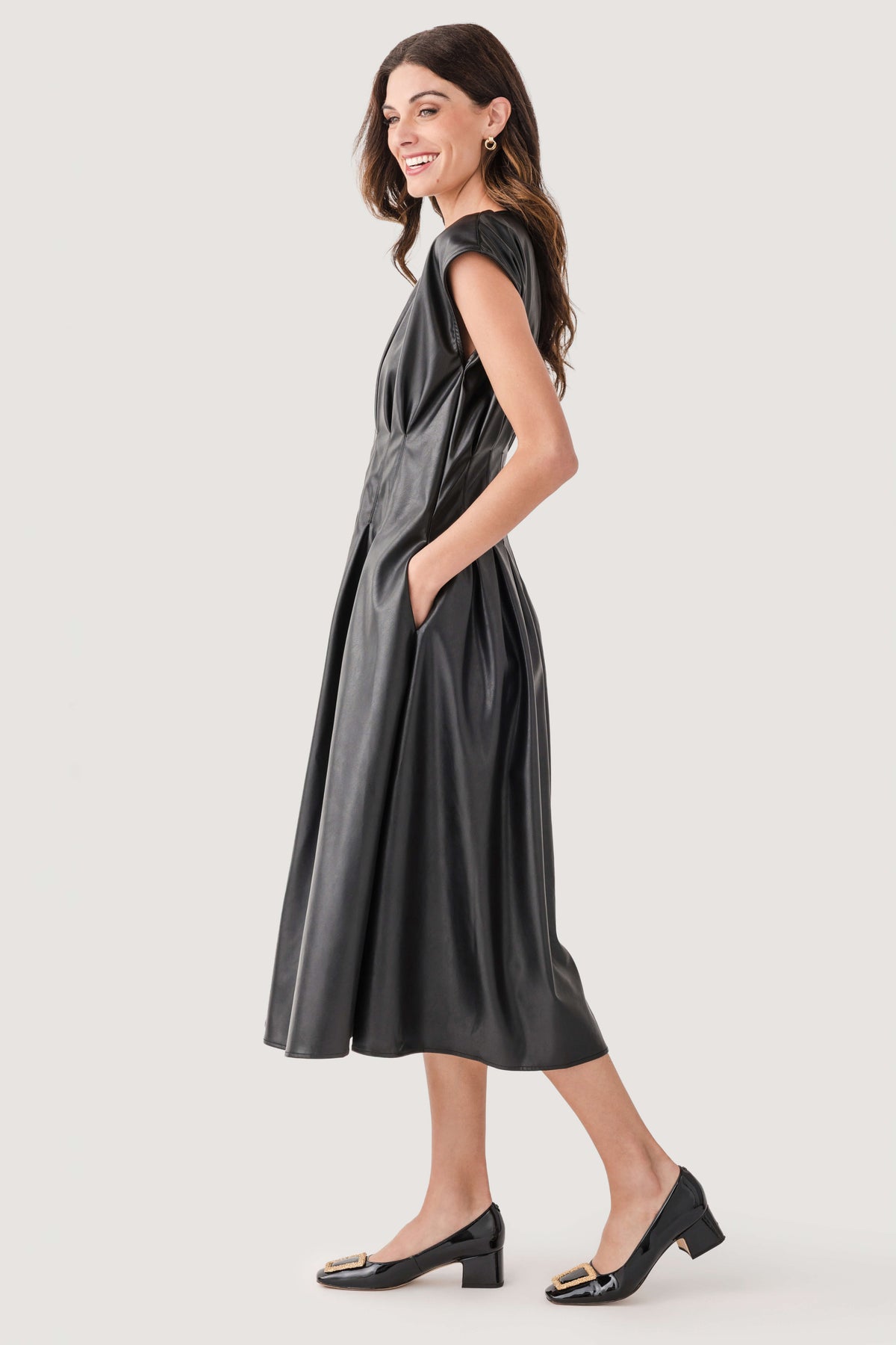 Black faux-leather pleated midi dress, sleeveless with princess seams, side view.