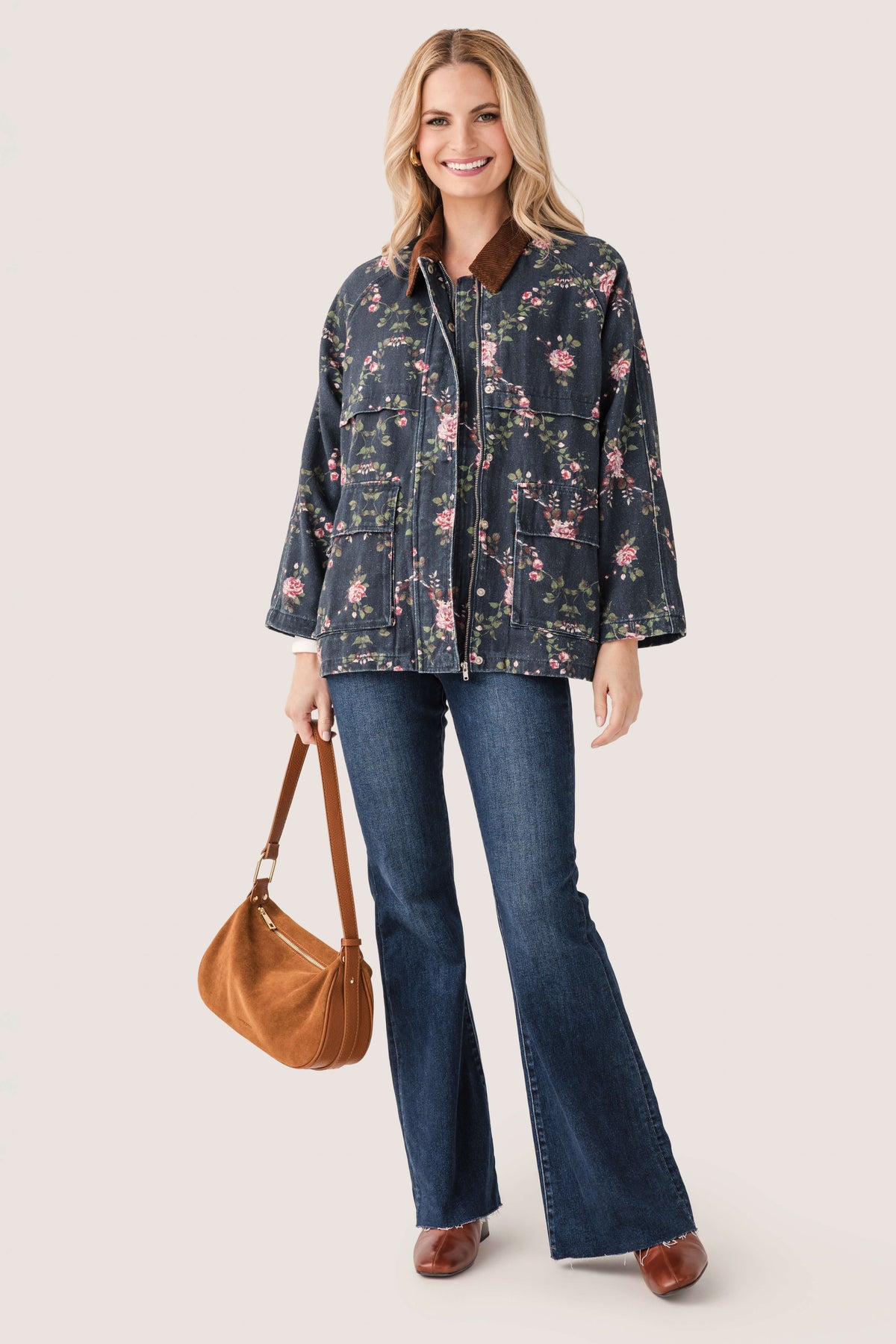 Floral printed utility jacket with full zipper and flap pockets, dark navy background.