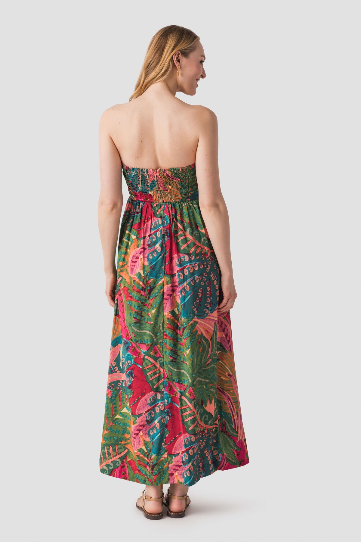 Back view of strapless ruched maxi dress in tropical print, low back and gathered skirt.