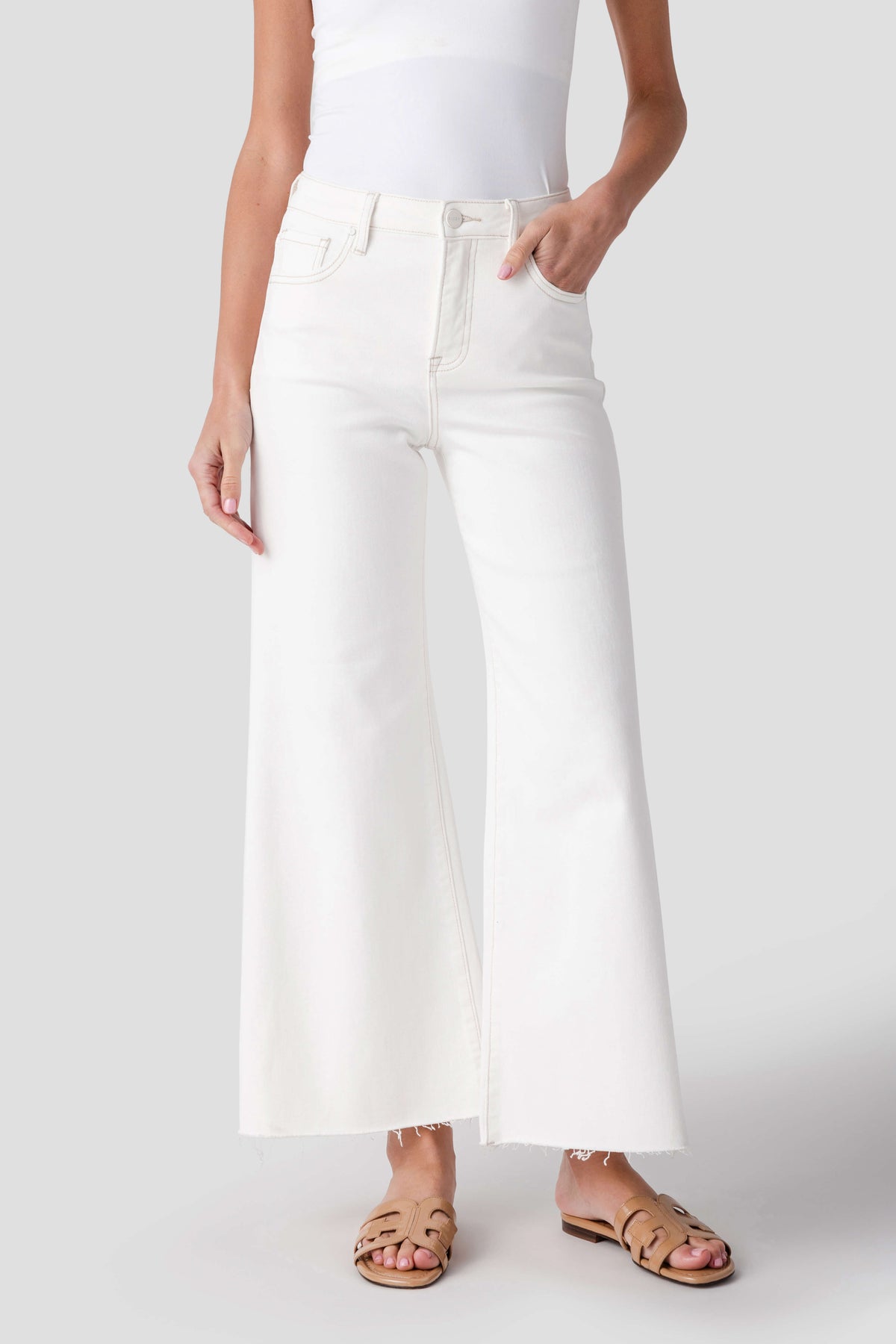Cream palazzo pants with side seams, front pockets, and raw-cut hem edge
