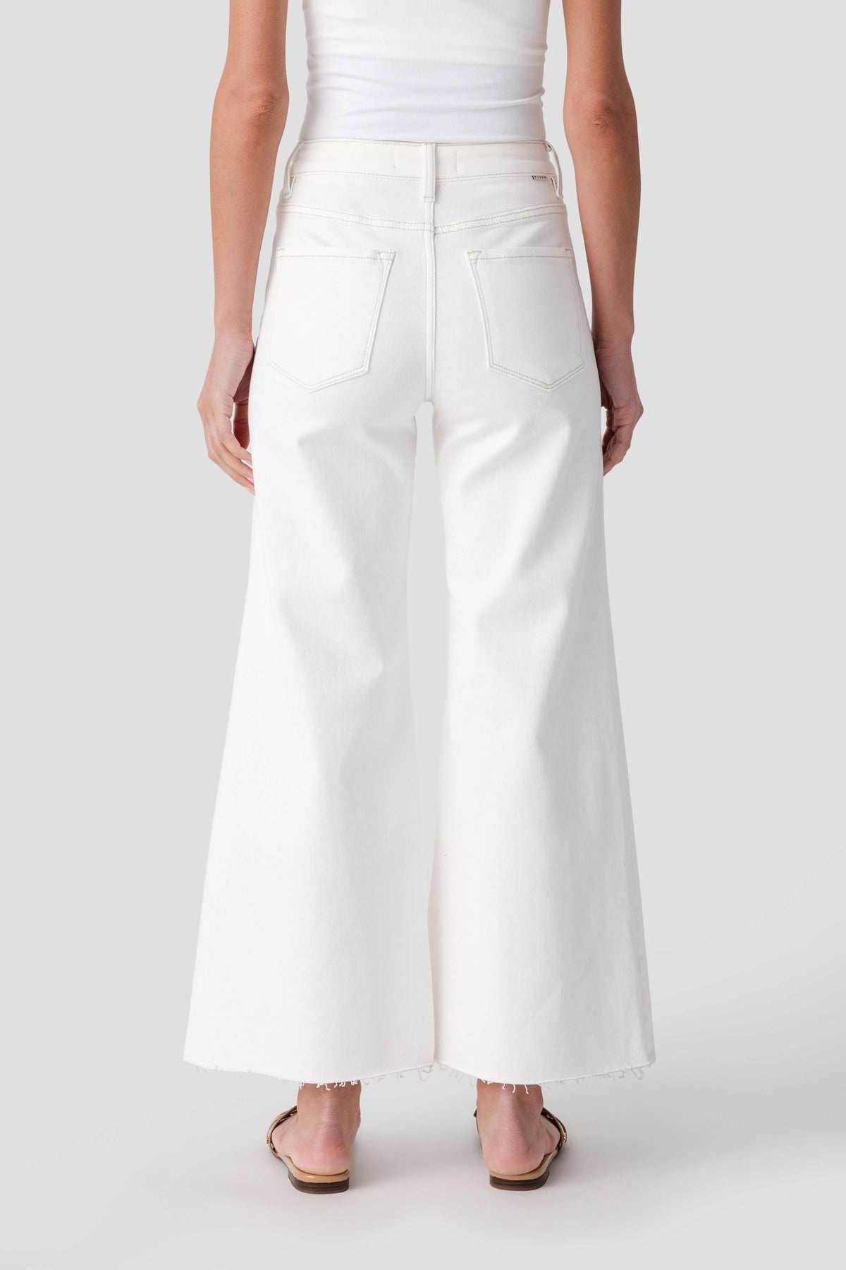 Cream palazzo pants with back pockets and raw hem at the ankle