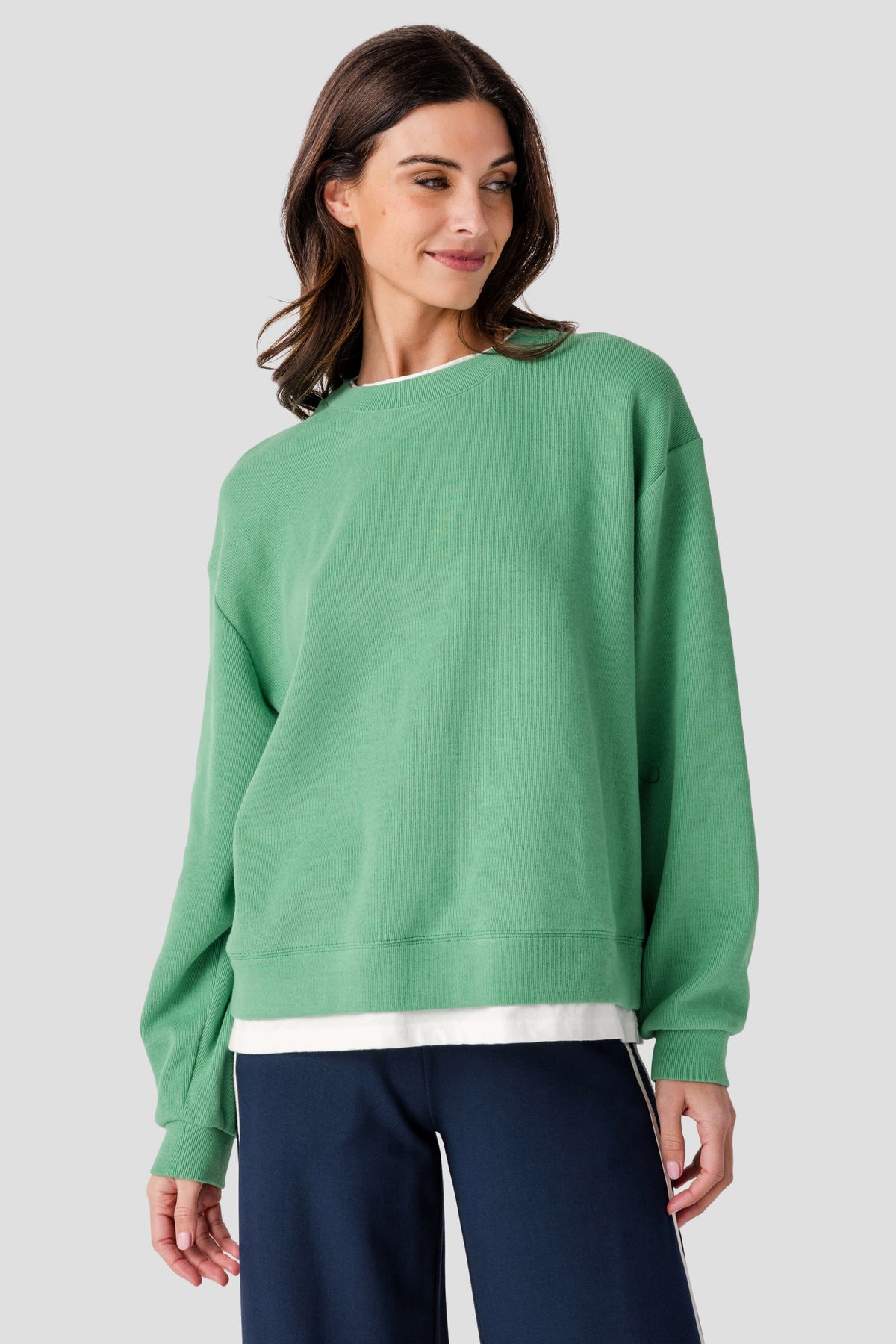 Green crewneck pullover with ribbed cuffs and hem, white trim at bottom edge, side angle
