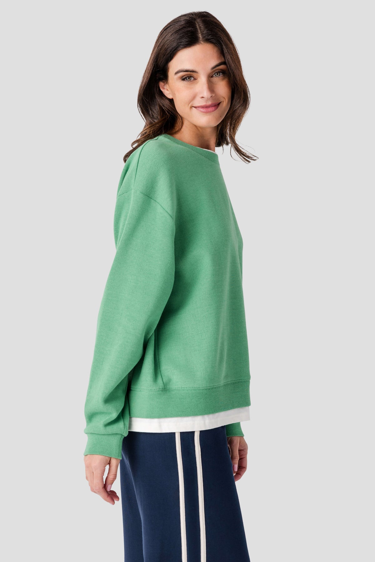 Green crewneck pullover with ribbed cuffs and hem, side view showing white bottom trim