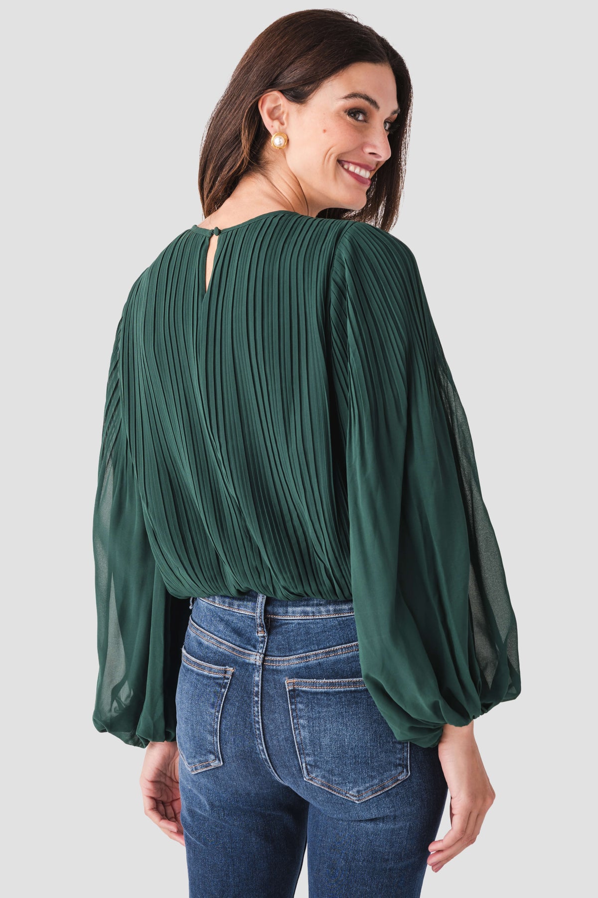 Back view of pine green bubble hem top with vertical pleats and balloon sleeves