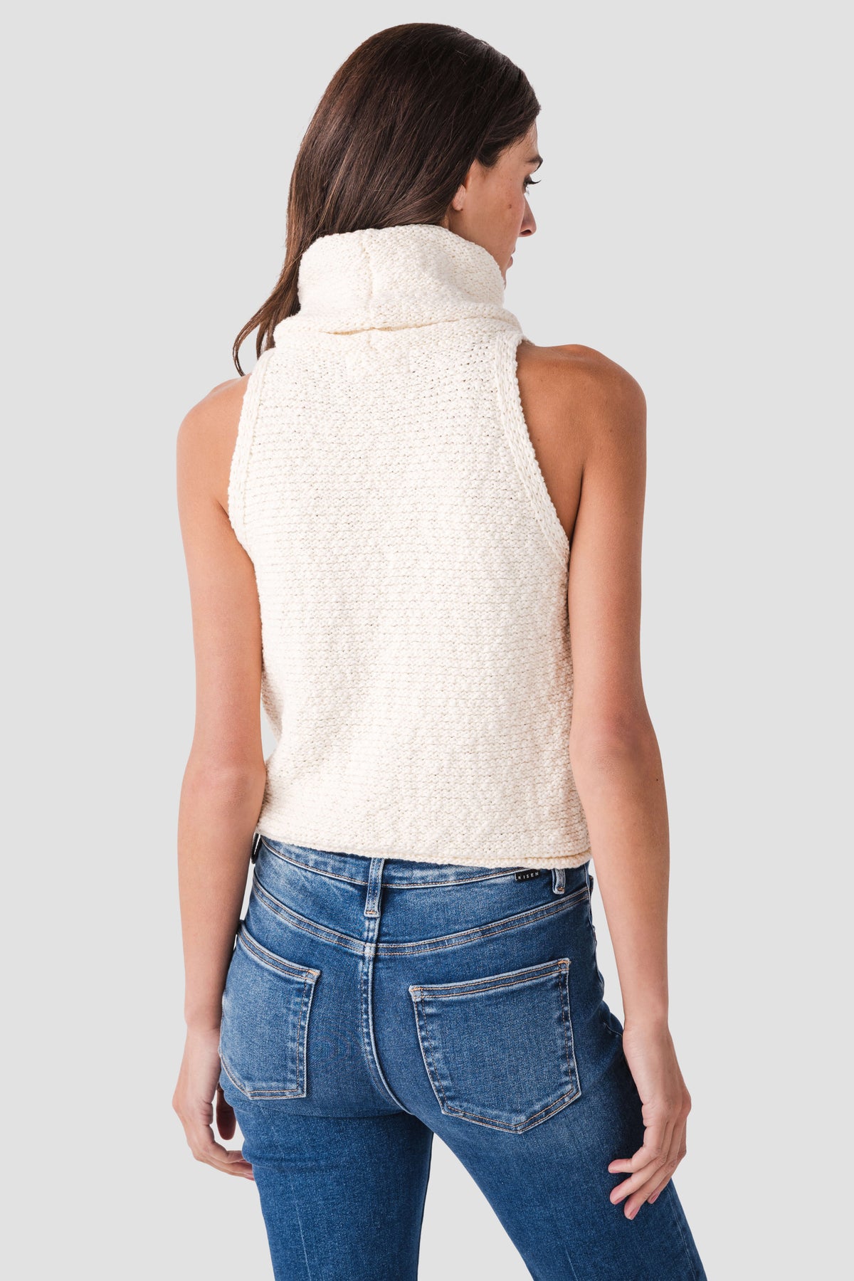 Back view of ivory sleeveless knit top with high neck cowl
