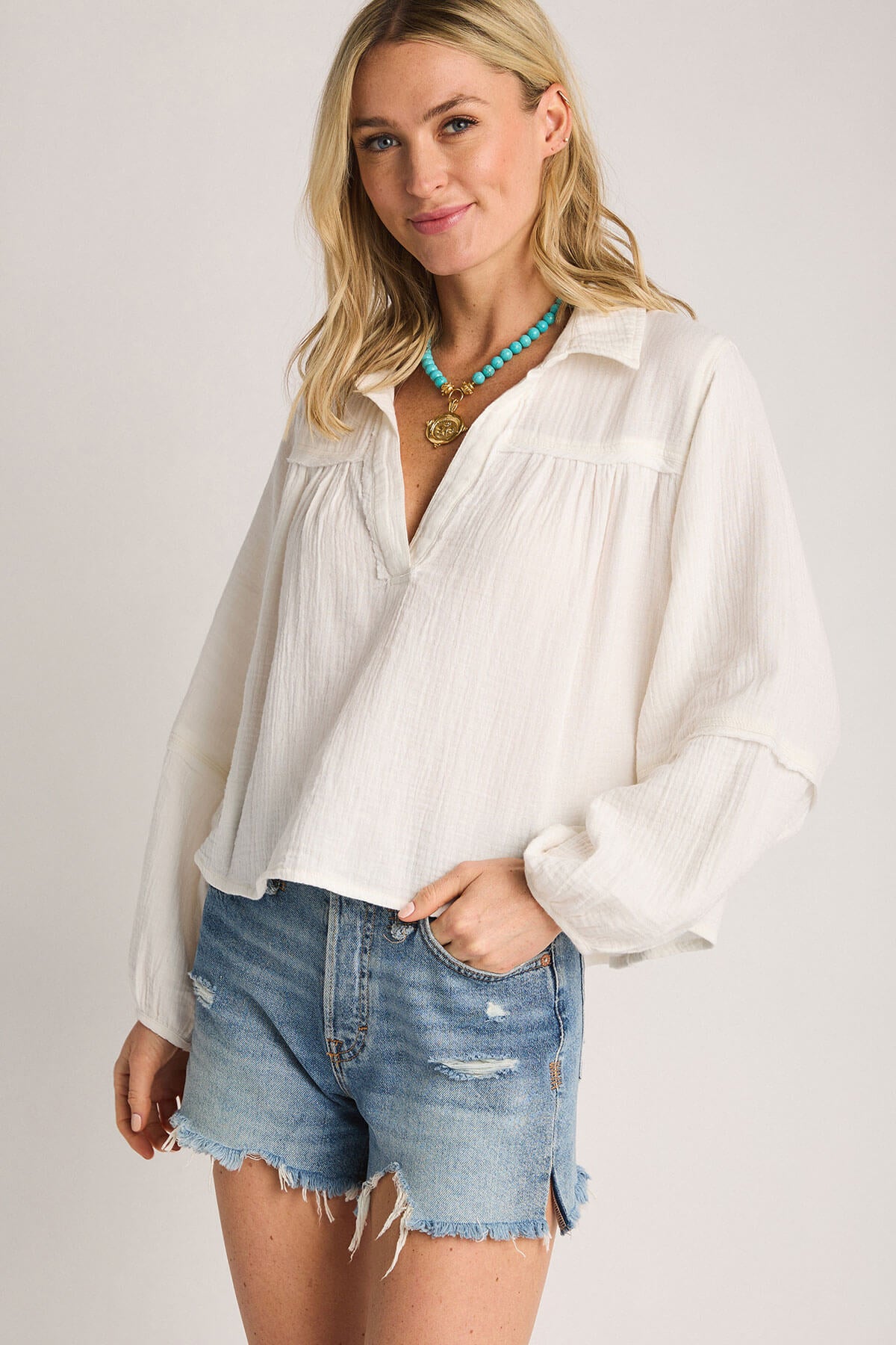 Turquoise bead bee pendant necklace worn on a model with a white blouse