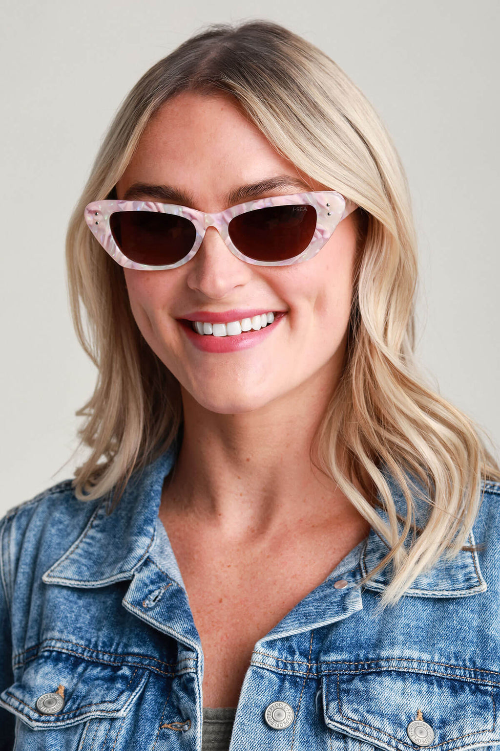 Cat-eye sunglasses with pink translucent frame and dark lenses, front view