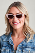 Cat-eye sunglasses with pink translucent frame and dark lenses, front view